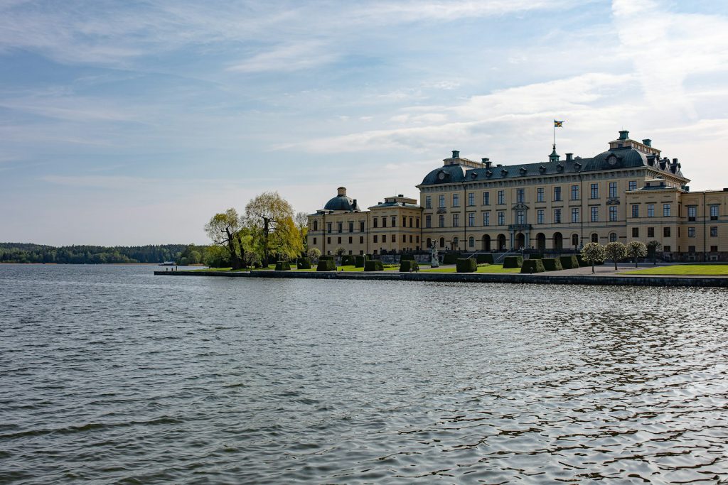 a large building sitting on the side of a lake drottningholm kasteel slot 