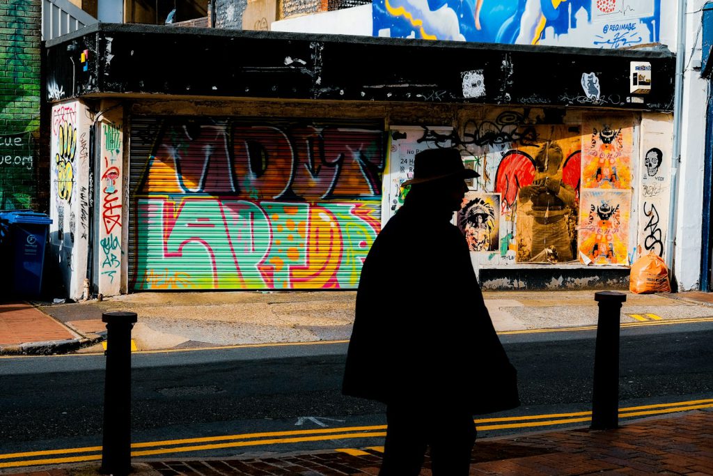 person in black coat walking on sidewalk during daytime north laine